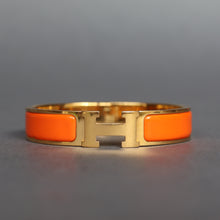 Load image into Gallery viewer, Vintage Hermes yellow gold bangle bracelet. Hermes clic clac. Hermes Clic H bracelet in orange enamel. Size small.