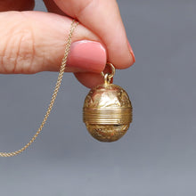 Load image into Gallery viewer, Antique Victorian era oval-shaped pendant in 15ct gold with repousse and foliate engraving. Locket spins to reveal hidden secret glass compartment.