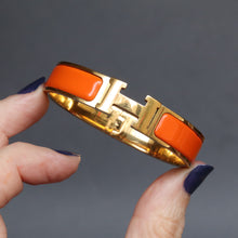 Load image into Gallery viewer, Vintage Hermes yellow gold bangle bracelet. Hermes clic clac. Hermes Clic H bracelet in orange enamel. Size small.

