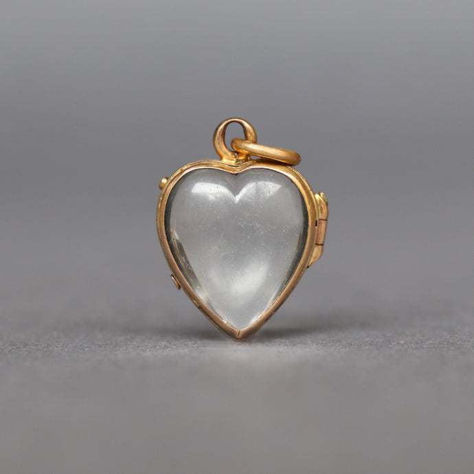 antique glass puffy heart locket dating Victorian era. Two glass leaves held in a hinged bracket with yellow gold gilding. It opens to allow flat items (photos, pressed flowers) to be placed inside.