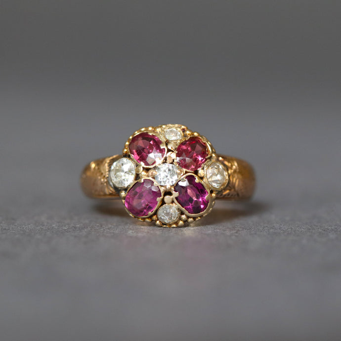 Antique Victorian era cluster ring with oval cut garnets and old cut diamonds in a flower design with a rose gold band.