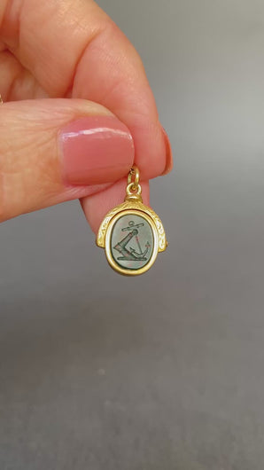 Antique bloodstone spinner fob pendant with intaglio depicting and knight's armored arm rising from the water holding an anchor. The monogram initials on the other side are MJ. Has a gold frame engraved and made from 18ct gold.