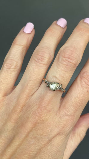 An antique diamond ring featuring a large pear-cut diamond set in a silver cut down collet with foil back and  small accent diamonds and a gold band. Perfect engagement ring.
