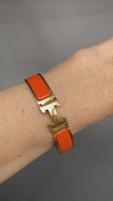 Load and play video in Gallery viewer, Vintage Hermes yellow gold bangle bracelet. Hermes clic clac. Hermes Clic H bracelet in orange enamel. Size small.
